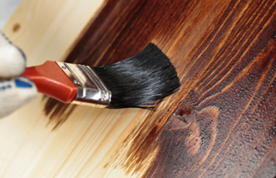Brush applying stain to wood